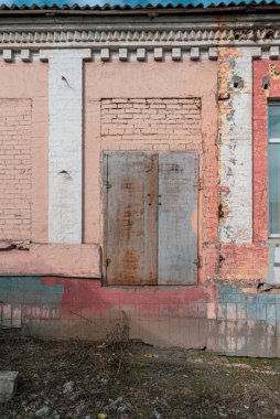 Beyaz sahte sütunları ve paslı metal kapısı olan terk edilmiş binalardan oluşan Grunge tuğlası bir duvar. Ev cephesinin yeniden yapılandırılması gerekiyordu