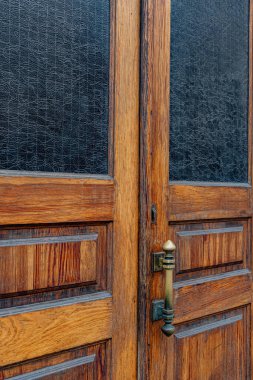 Dikdörtgen pencereli ahşap çift kapılı paneller ve çerçevelerin içinde mat desenli camlar. Grunge Old Wood Doku 'nun metal kapı kolu yakın plan. Kopya alanı olan dış yapı ayrıntıları