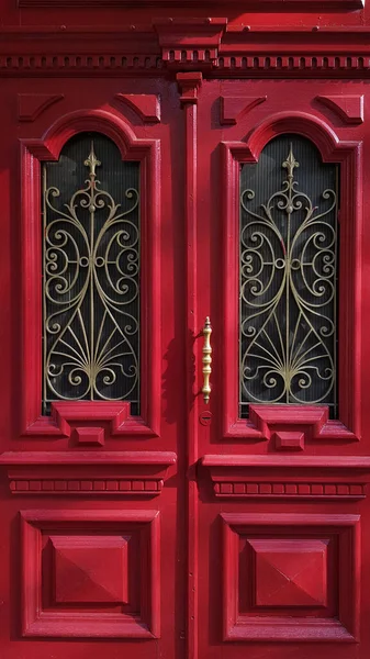 Closeup of antique red door panels with ornate frames and baroque metal gratings. Heritage of historic building in European city Odessa of Ukraine