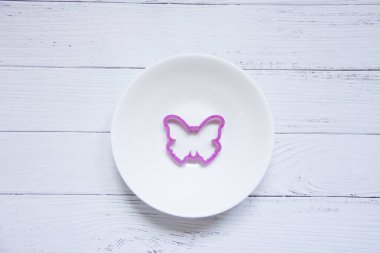 Beyaz arka planda plastikten yapılmış mor kelebek şekli. Çocukların plastikçilik formları..