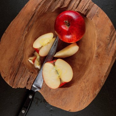 Olgun Kırmızı elma bir bıçakla arduvaz levha zemin ahşap bir kasede yarım kesilmiş 