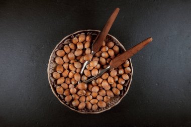 Karanlık arduvaz levha zemin üzerine bir kase yemek için taze, olgun fındık hazır