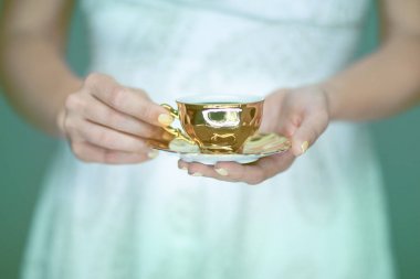 beautiful woman hands holding vintage antique tea cup, sensual atmospheric studio shot clipart
