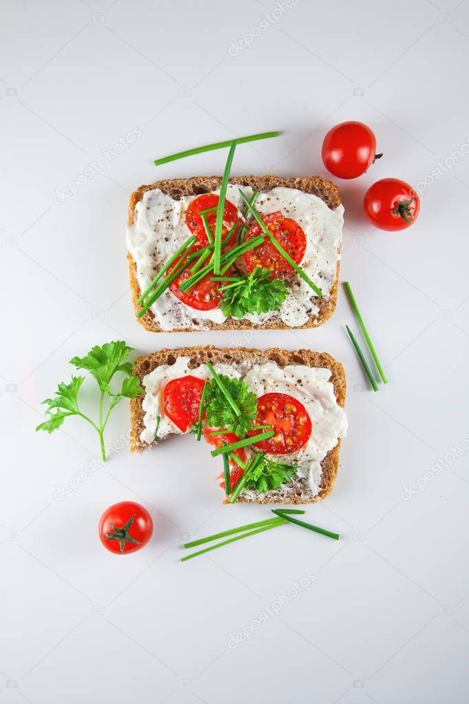 freshly prepared bread slices with cream cheese, tomatoes and chives