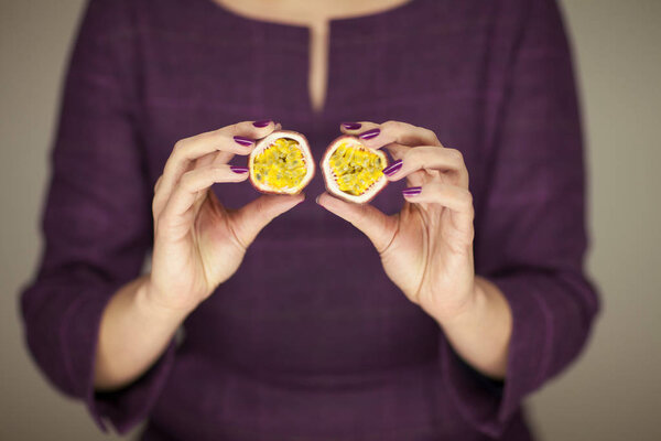 женщина в платье руки фиалки 50 's держа некоторые фрукты страсти, чувственный студийный снимок может быть использован в качестве фона
