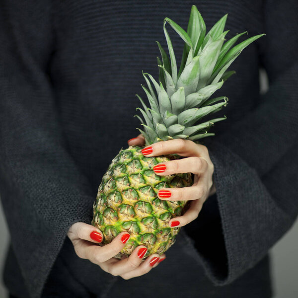 Женские руки с ананасом, чувственный студийный снимок может быть использован в качестве фона
