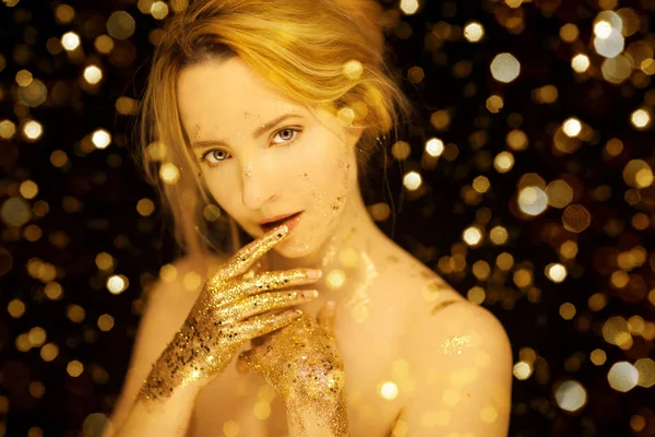 Beautiful woman in gold, golden hands, glitter sensual glamour studio shoot