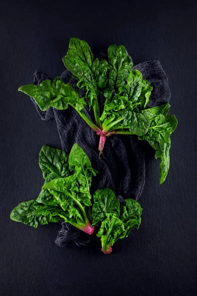 freshly harvested spinach on dark kitchen plate and napkin can be used as background