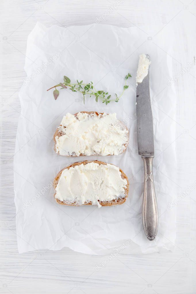 freshly prepared bread cut with cream cheese on white paper can be used as background