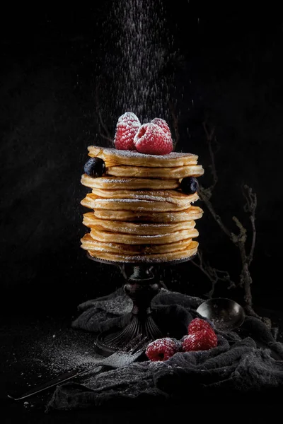 a stack of pancakes decorated with berries and powdered sugar, rustic studio shot, can be used as background