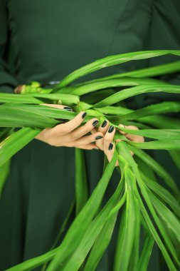 Yeşil 50 's kadın elbise şehvetli stüdyo çekim arka plan olarak kullanılan bazı tropikal yaprak, holding eller