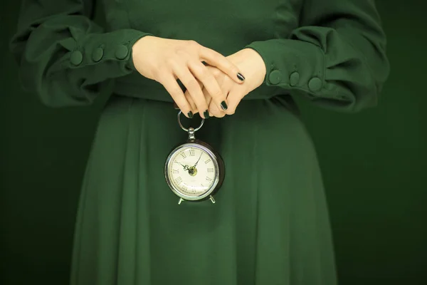 美丽的女人身材绿色的衣服与绿色背景举行复古钟 色调绿色 — 图库照片