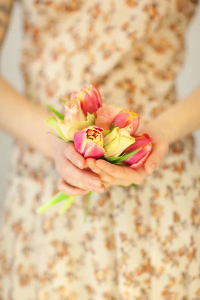 woman hands holding spring flowers tulips and roses, spring flower dress, sensual studio shot can be used as background