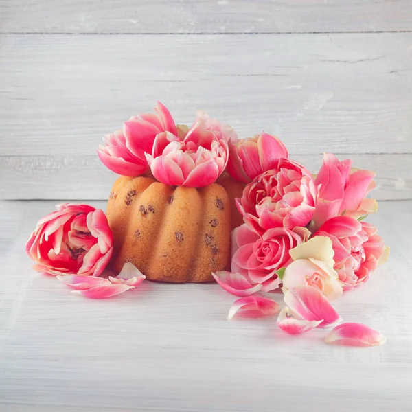 小さなケーキ スタジオ ショットは 背景として使用できる春の花チューリップやバラ 木製ホワイト キッチン プレートの上にパイ — ストック写真