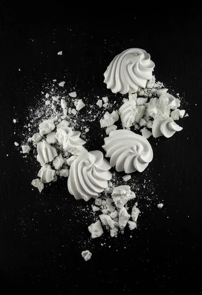 白色蛋白甜饼糖果在黑色石板板厨房桌可以作为背景 — 图库照片