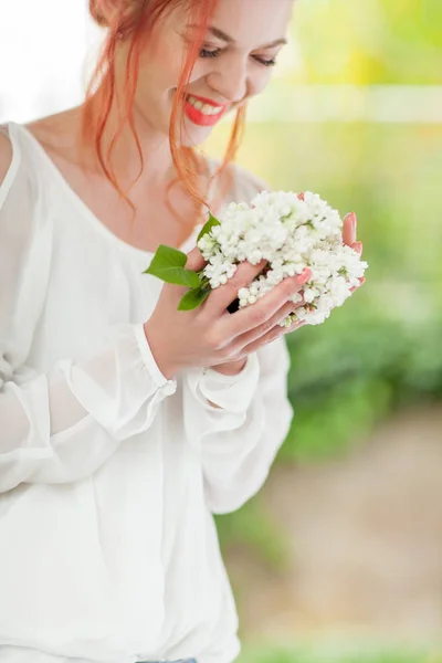 香りの良い臭いがする 手に白いライラックの花を持った赤い髪の美しい女性 — ストック写真
