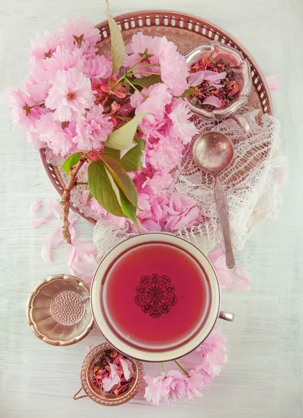 vintage, antique cup of fruit tea decorated with cherry flowers on white background in a shabby chic look