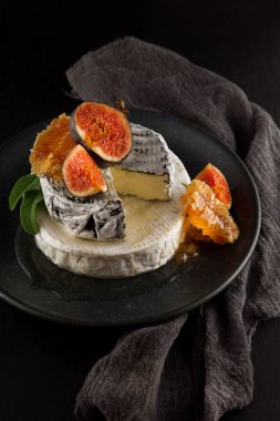 taze incir ile lezzetli camembert ve bal peteğin ile dekore edilmiş, rustik, koyu arka plan üzerinde bir tabakta moody gıda fotoğrafçılığı