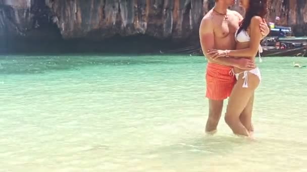 Парень и девушка стоят обнявшись в грязной воде у скалы — стоковое видео