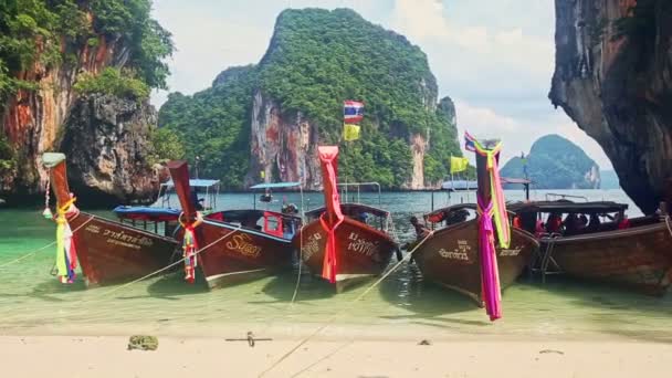 Barcos de cauda longa tailandeses em mar raso pela praia contra falésias verdes — Vídeo de Stock