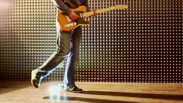 Guy suona la chitarra in studio rubinetti tacchi alla luce brillante — Video Stock