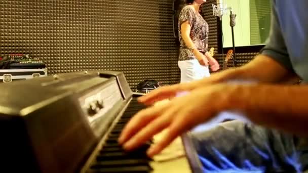 Крупним планом хлопець грає на піаніно дівчина співає на репетиції в студії — стокове відео