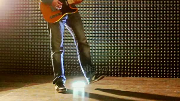 Adam gitar Studio musluklar topuklarla parlak ışıkta çalış — Stok video