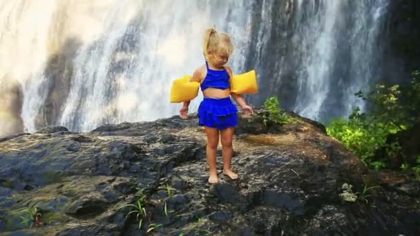 Menina pequena contra grande cachoeira — Vídeo de Stock