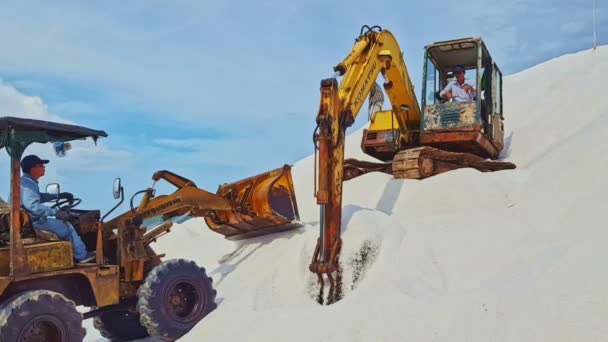 Grävmaskin och traktor på stora högen av salt — Stockvideo