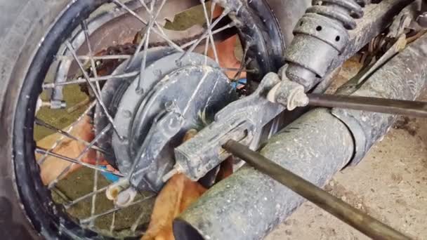 Мужчина врезался в колесо мотоцикла в ремонтной мастерской — стоковое видео