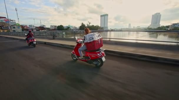 Девушка водит скутер с корзиной на обратно вдоль улицы утром — стоковое видео
