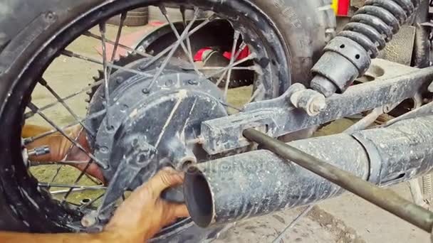 Hombre monta rueda a motocicleta en taller de reparación — Vídeo de stock