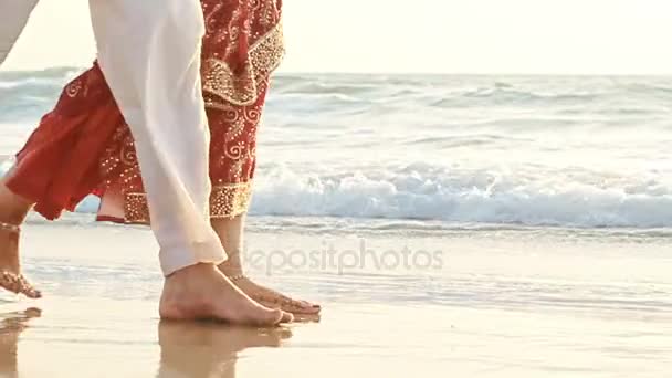 Man met een meisje lopen op blote voeten in het water langs het strand — Stockvideo