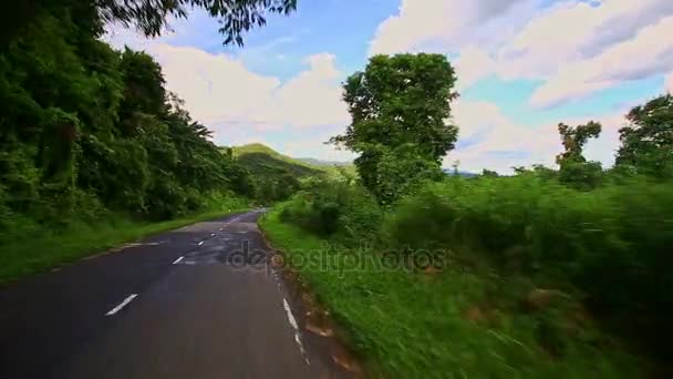 Mișcare în jos drum cu iarbă pe marginea drumului printre peisajul deluros — Videoclip de stoc