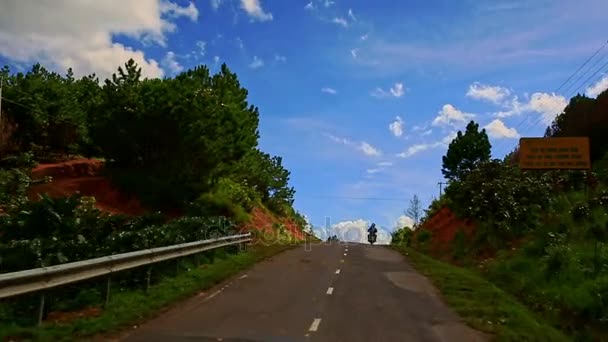 Mouvement vers le bas de la route avec de l'herbe sur le bord de la route parmi le paysage vallonné — Video