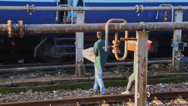 Män med plastlådor promenera längs järnvägsspår — Stockvideo