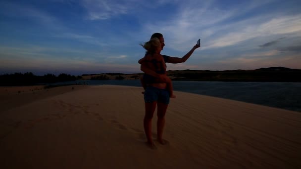 Madre sostiene chica en brazos en duna — Vídeo de stock