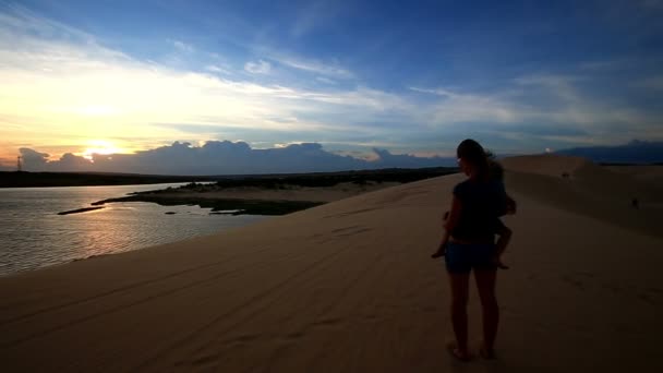 Madre sostiene chica en brazos en duna — Vídeo de stock