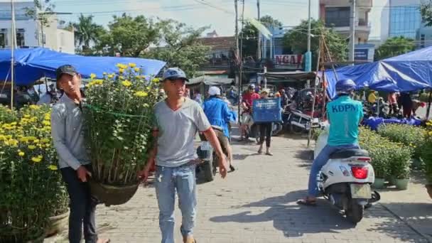 Mannen dragen chrysant bloempot in straatmarkt — Stockvideo