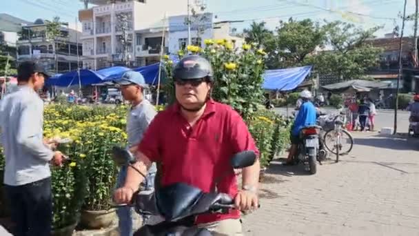 Adam kasımpatı çiçekleri scooter üzerinde tencerede taşır — Stok video