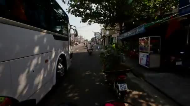 Aziatische man op motor langs schaduwrijke straat — Stockvideo