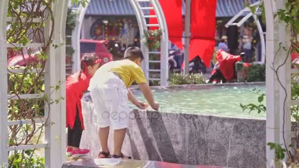 Boy and girl play at street fountain — Stock Video