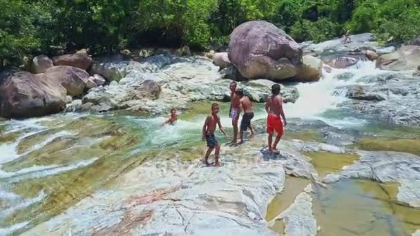 Мальчики скользят по камням горной скалистой реки — стоковое видео