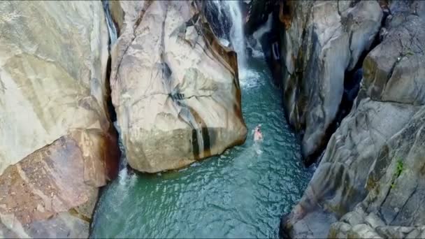 Homem nada na água entre rochas para cascata de cachoeira — Vídeo de Stock