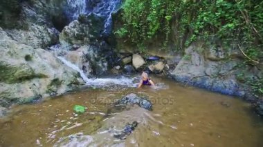şelale kayalar arasında yakınındaki akışındaki kız yüzüyor 