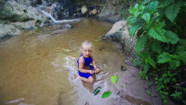 Tjej simmar i ström nära vattenfall bland stenar — Stockvideo
