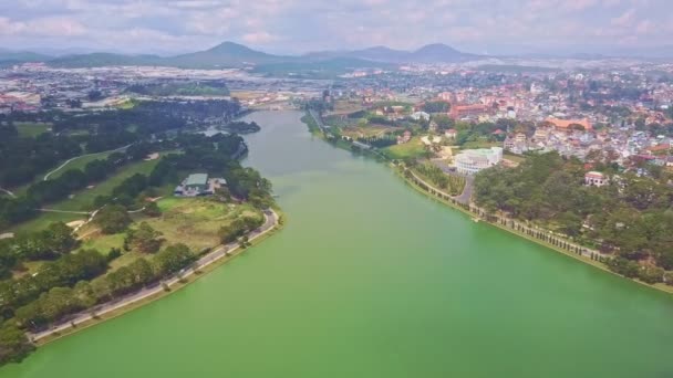 Озеро з лісами і газонами на берегах проти міста і гір — стокове відео