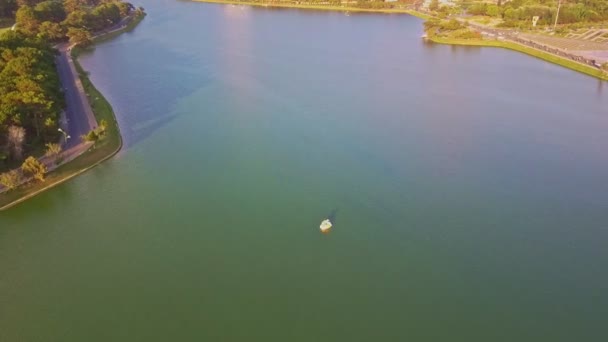 Σκάφος και λίμνη ανάμεσα σε καταπράσινο πάρκο εναντίον της πόλης — Αρχείο Βίντεο