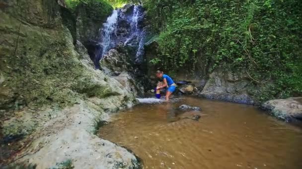 Mother and daughter play barefoot in stream water — Stock Video