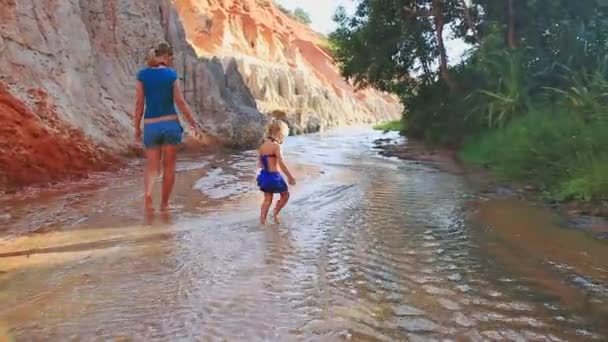 Moeder en dochter spelen blote voeten in het water van de stream — Stockvideo